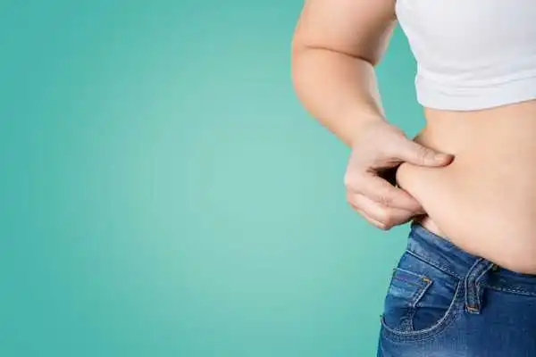 Image of woman pinching her love handles to show weight gain Bridgnorth