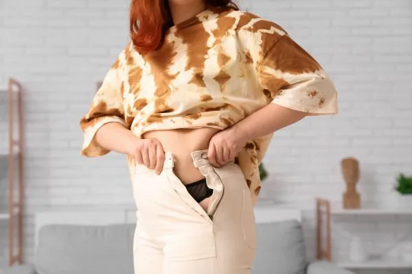 Image of woman trying to do her trousers up after pregnancy weight gain Bridgnorth